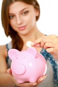 Young beautiful woman standing with piggy bank (money box)